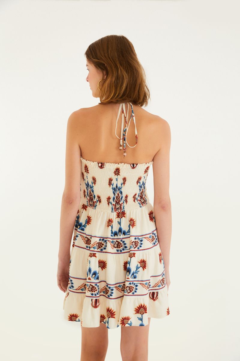 Vista trasera del vestido corto estampado mostrando los tirantes delgados y detalles florales.