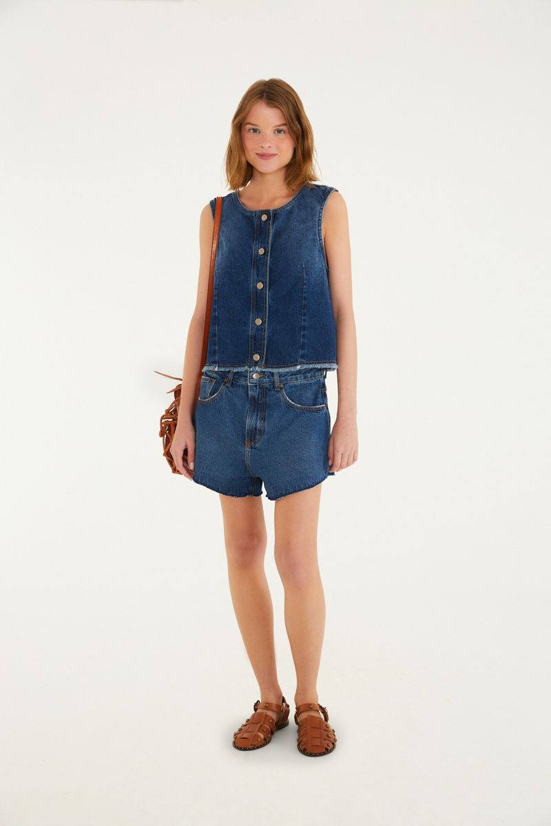 Imagen de un modelo vistiendo un conjunto de jeans con short y blusa sin mangas, mostrando el look completo.
