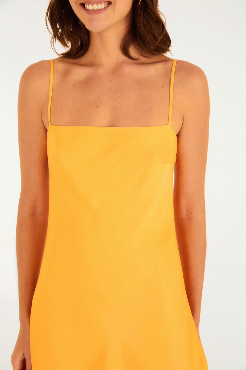 Primer plano del vestido corto amarillo mostrando detalles del escote cuadrado.