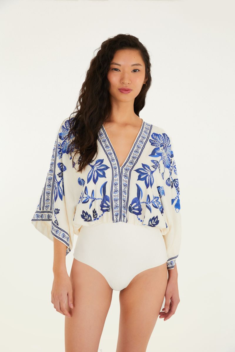 Body con estampado tropical azul y fondo beige, visto de frente.