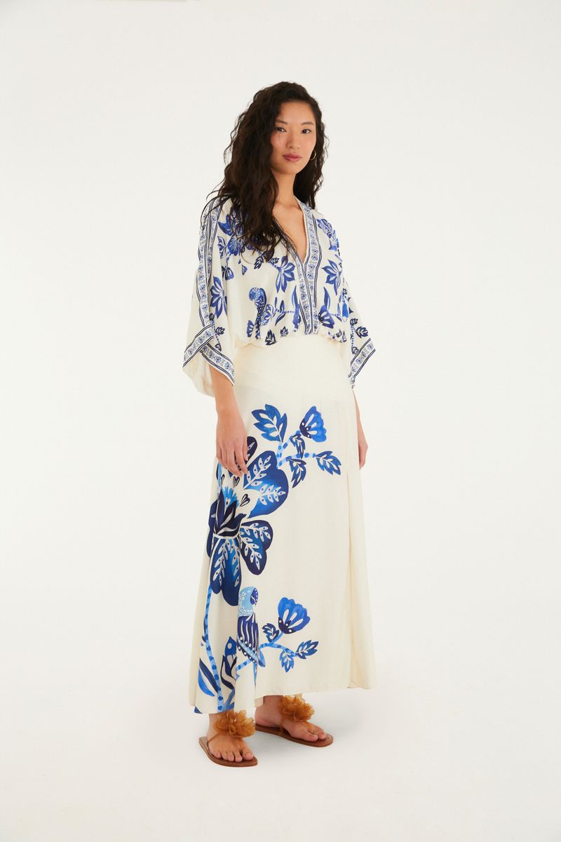 Body con estampado tropical azul y fondo beige, visto en conjunto con falda.