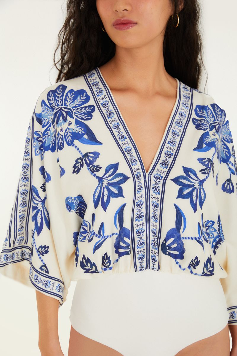 Detalle del escote en forma de V del body con estampado tropical azul.