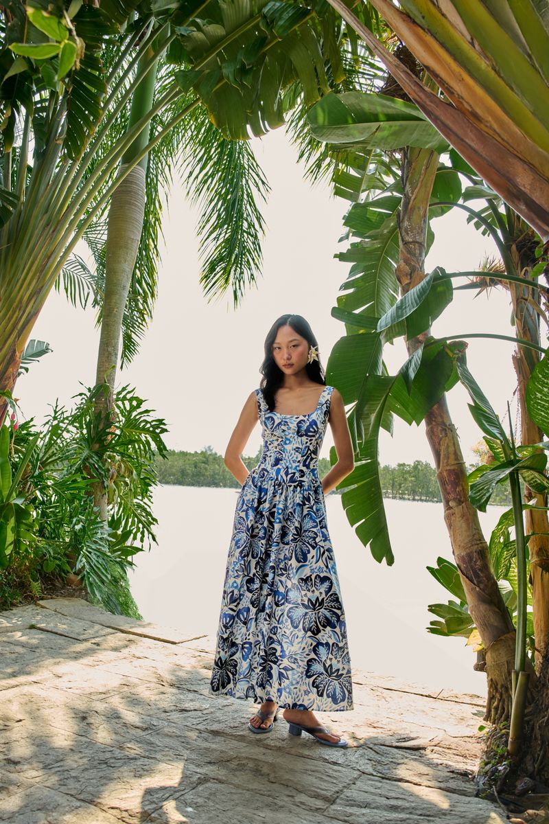Vestido largo estampado floral en azul y blanco, fotografiado en ambiente tropical.
