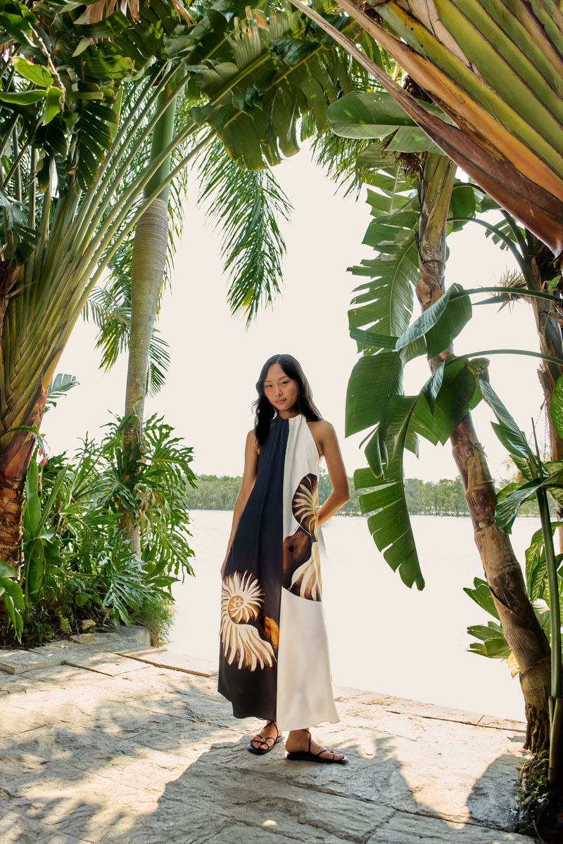 Modelo vistiendo un vestido largo con estampado de amonita en un entorno tropical.
