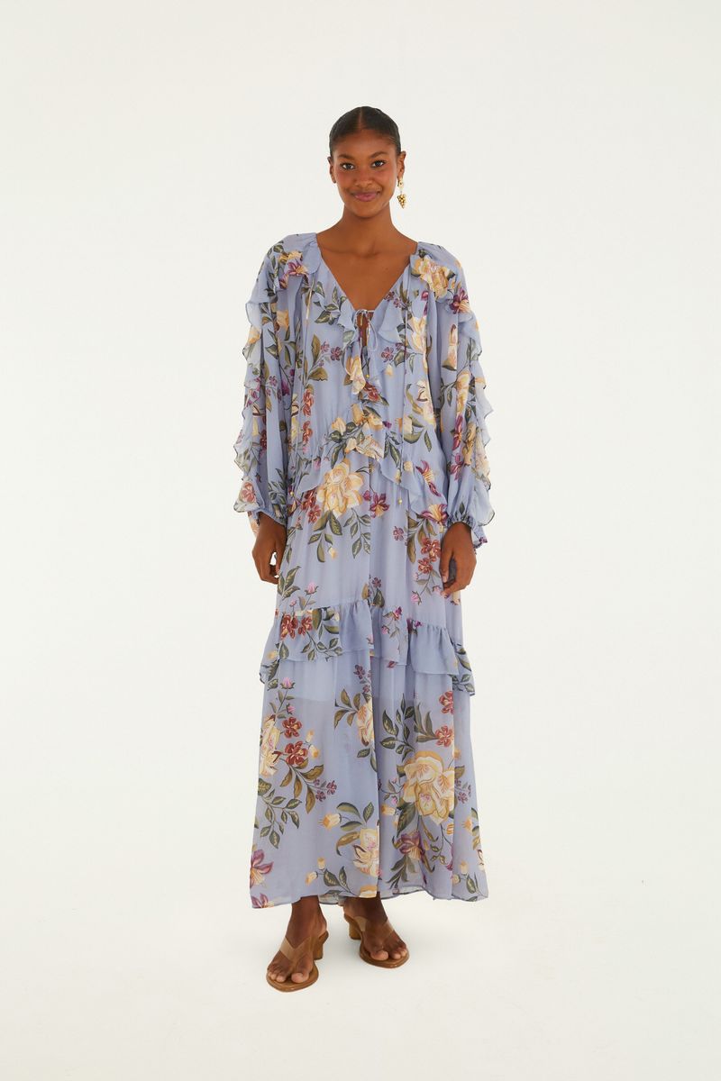 Vestido largo floral con volantes en fondo azul claro, mostrado de frente.