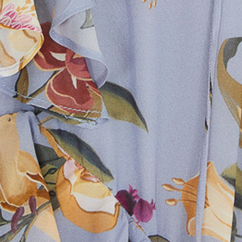 Primer plano del estampado floral del vestido en fondo azul claro.