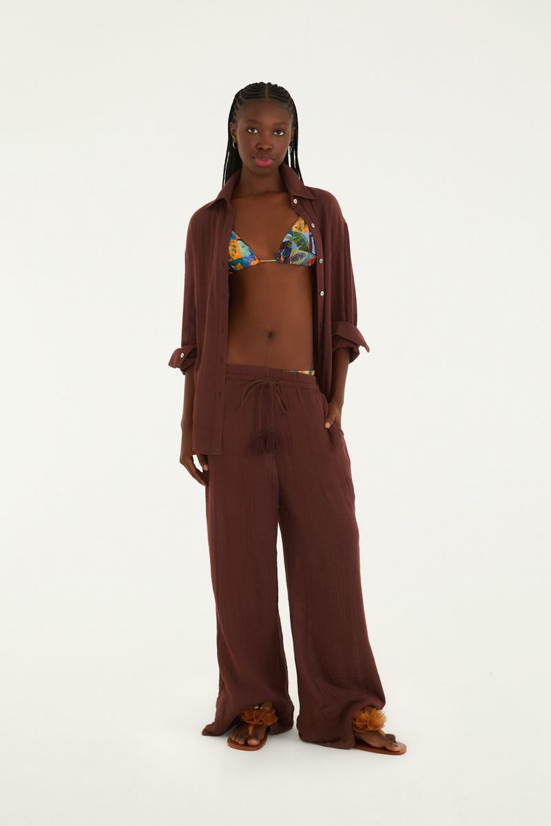 Modelo luciendo un pantalón marrón de textura ancha con camisa abierta y top estampado, vista frontal completa - pantalón ancho con cintura elástica y caída fluida