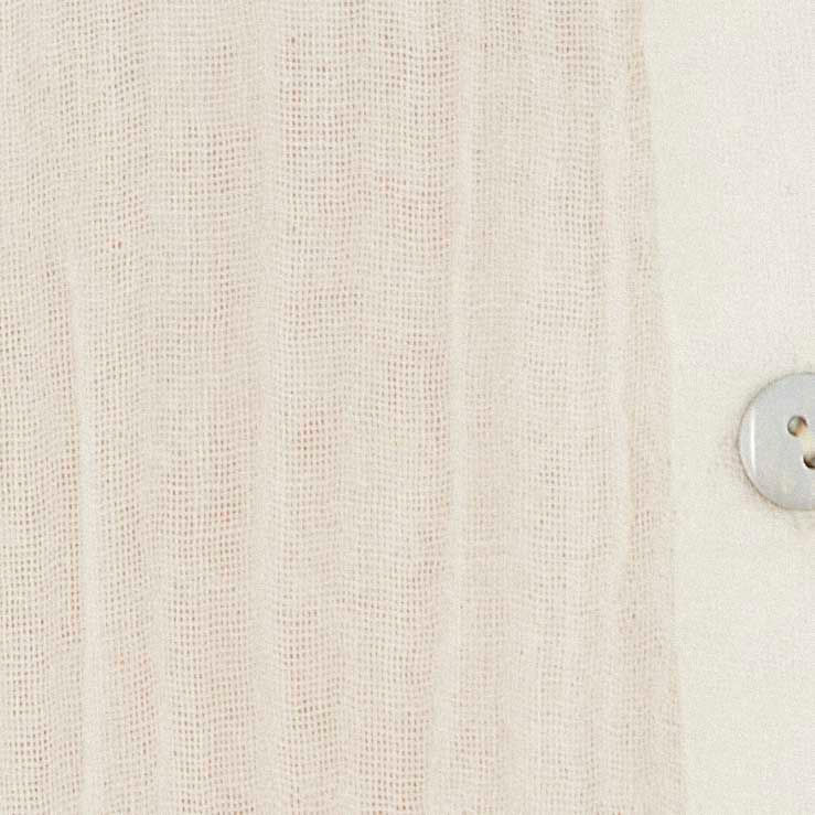 Detalle del tejido y textura crinkle de la tela en color crema, acercamiento del material mostrando surcos verticales.